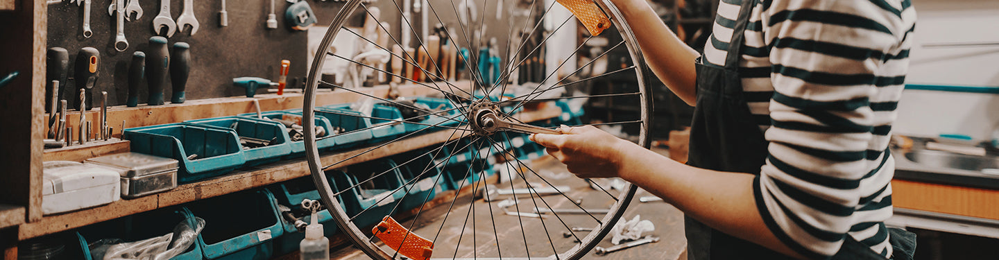 Personne dans un atelier vélo qui répare une roue avec des pièces détachées